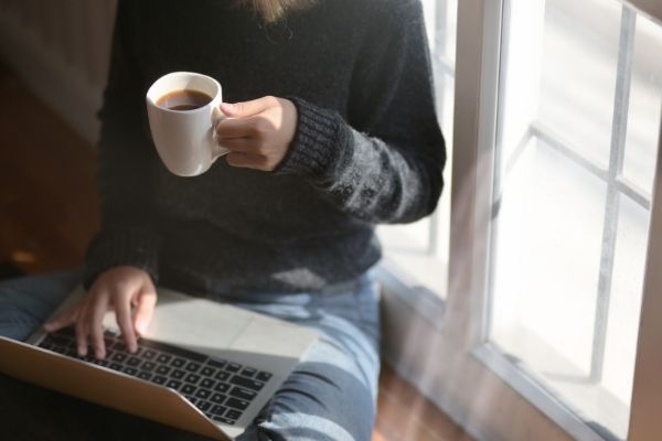 woman drinking coffee and working on laptop