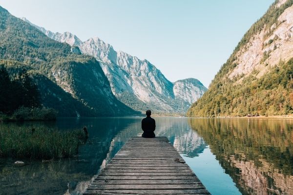 Man sitting on dock overlooking scenic lake